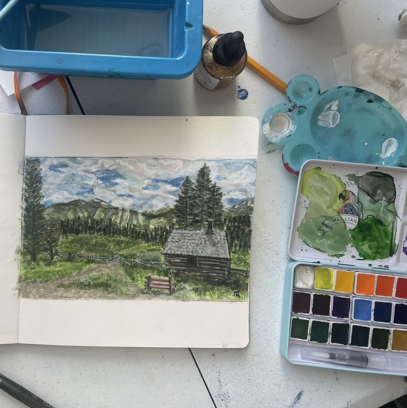 Jenny’s watercolor of Cucumber Gulch in her sketchbook, surrounded by her watercolor paints, palette and brushes