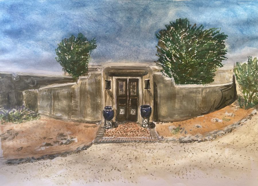 Santa Fe Adobe by Jenny W. Green: Adobe entry with carved wooden doors flanked by cobalt blue pots, trees behind the wall